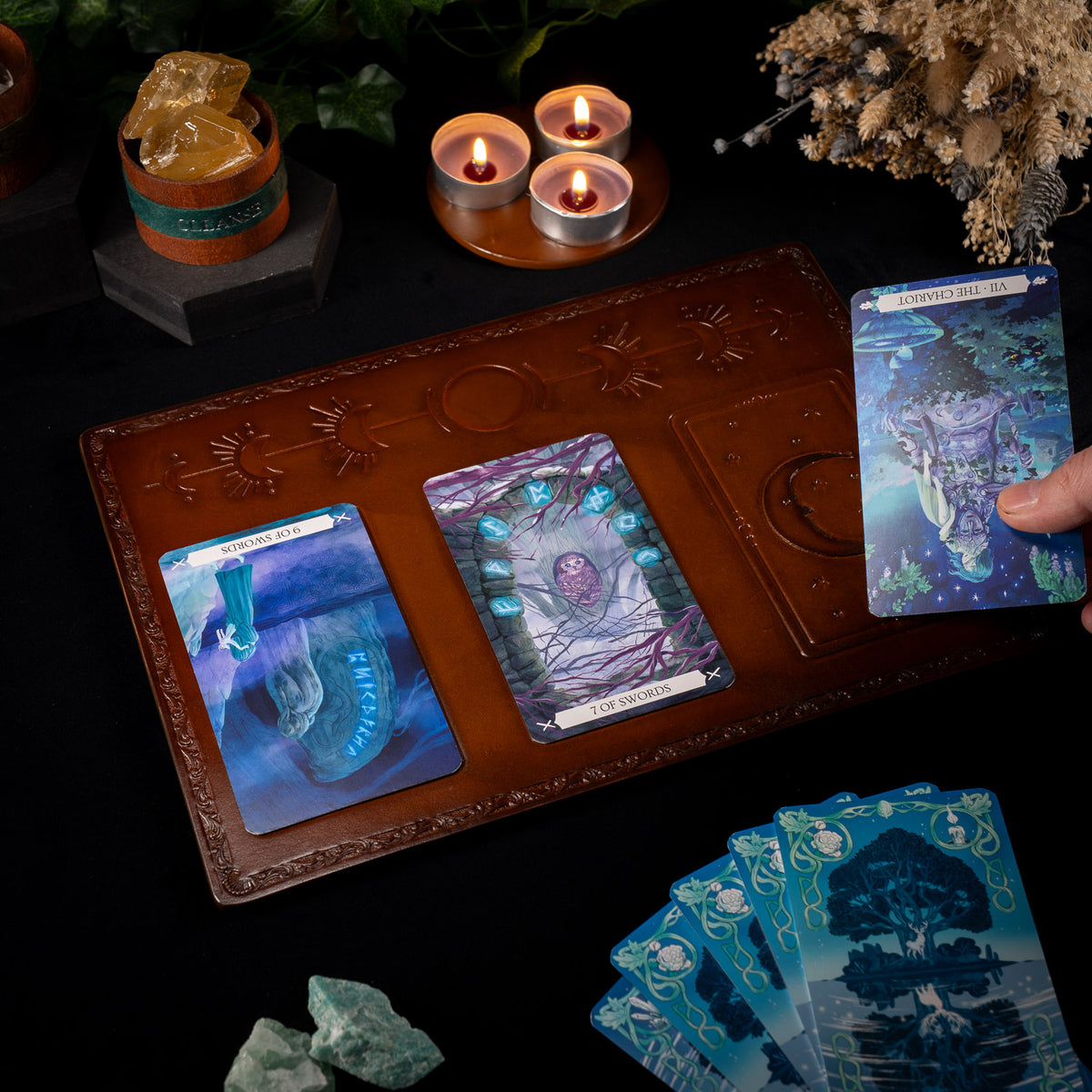 A hand laying the third card of a three-card tarot spread on The Astro leather tarot mat