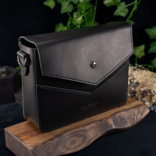 Black handmade leather shoulder bag with recessed chevron channel, front view