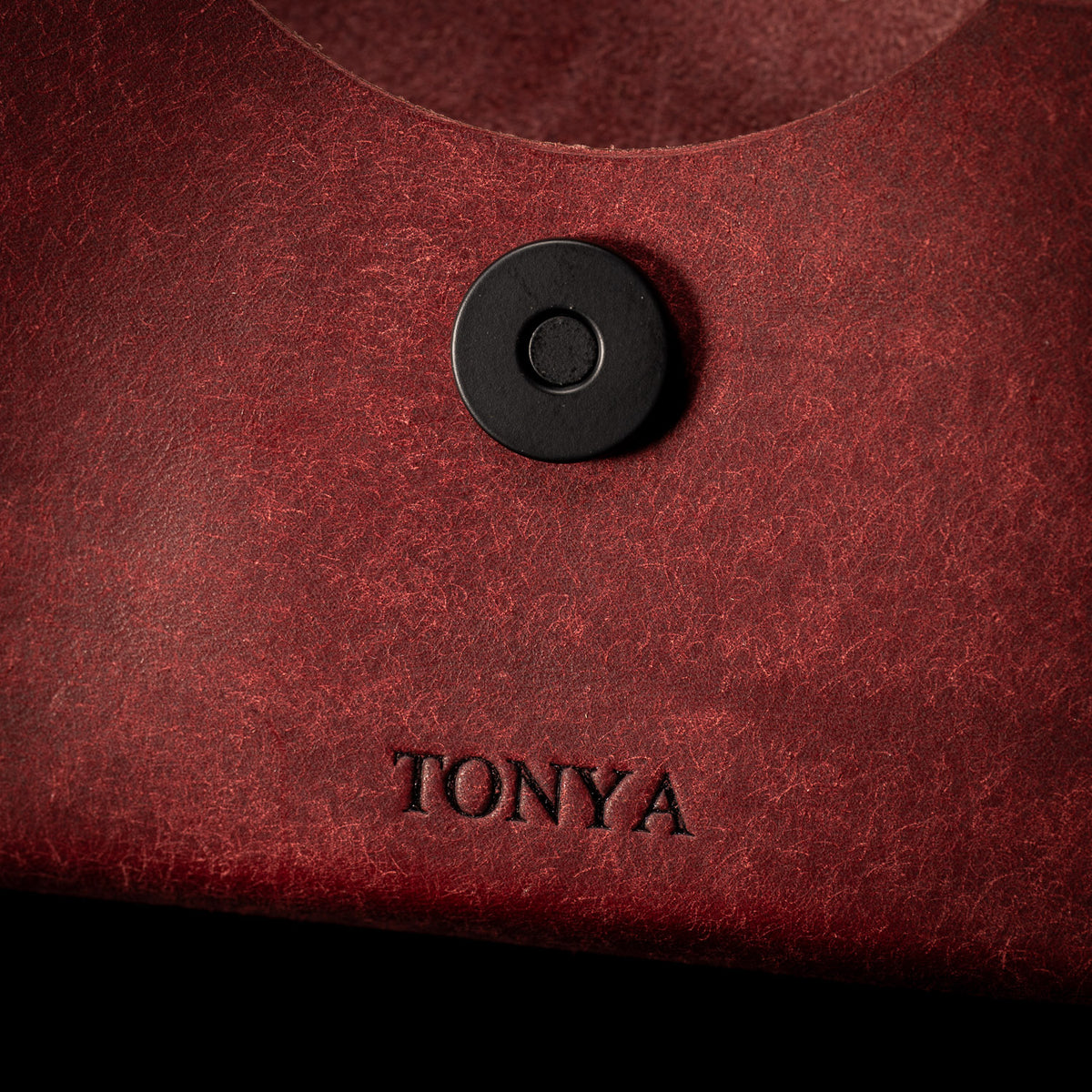 Close up of a red Fire case personalised with an embossed name below a matte black magnetic snap