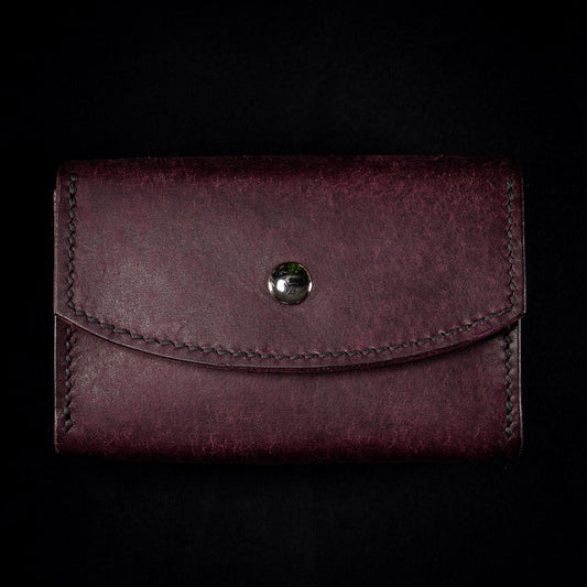 The Oracle deck case in plum Prugna leather, the Cosmic colourway, photographed flat from the front against black