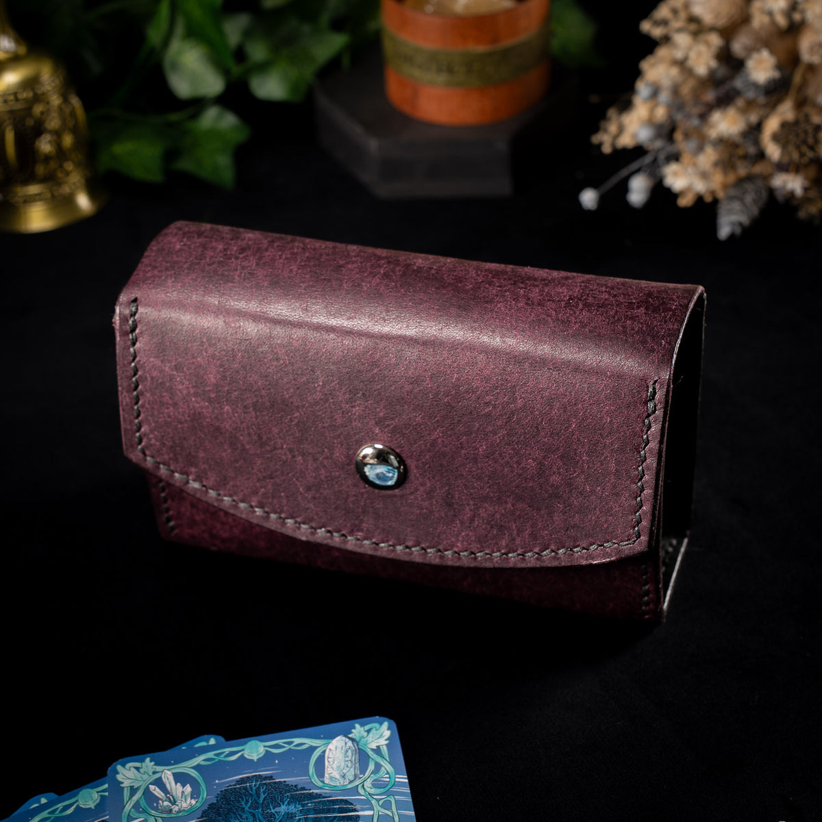 The Oracle deck case in plum Prugna leather, the Cosmic colourway, closed with black stitching and a silver stud