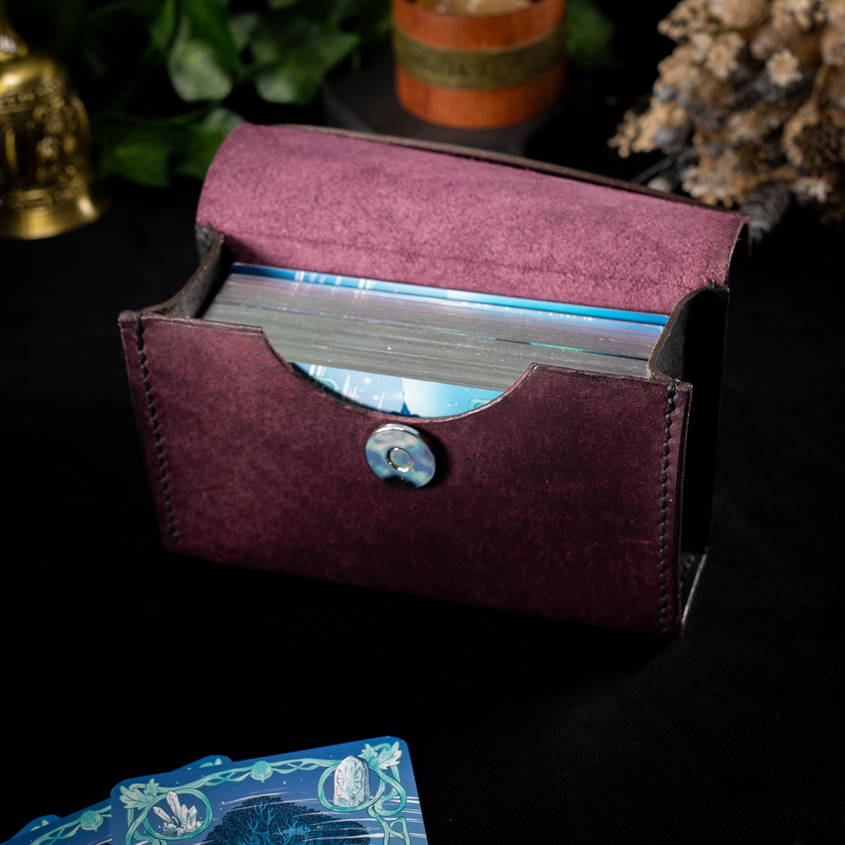 The Cosmic Oracle case open, a tarot deck standing upright inside behind the curved front recess