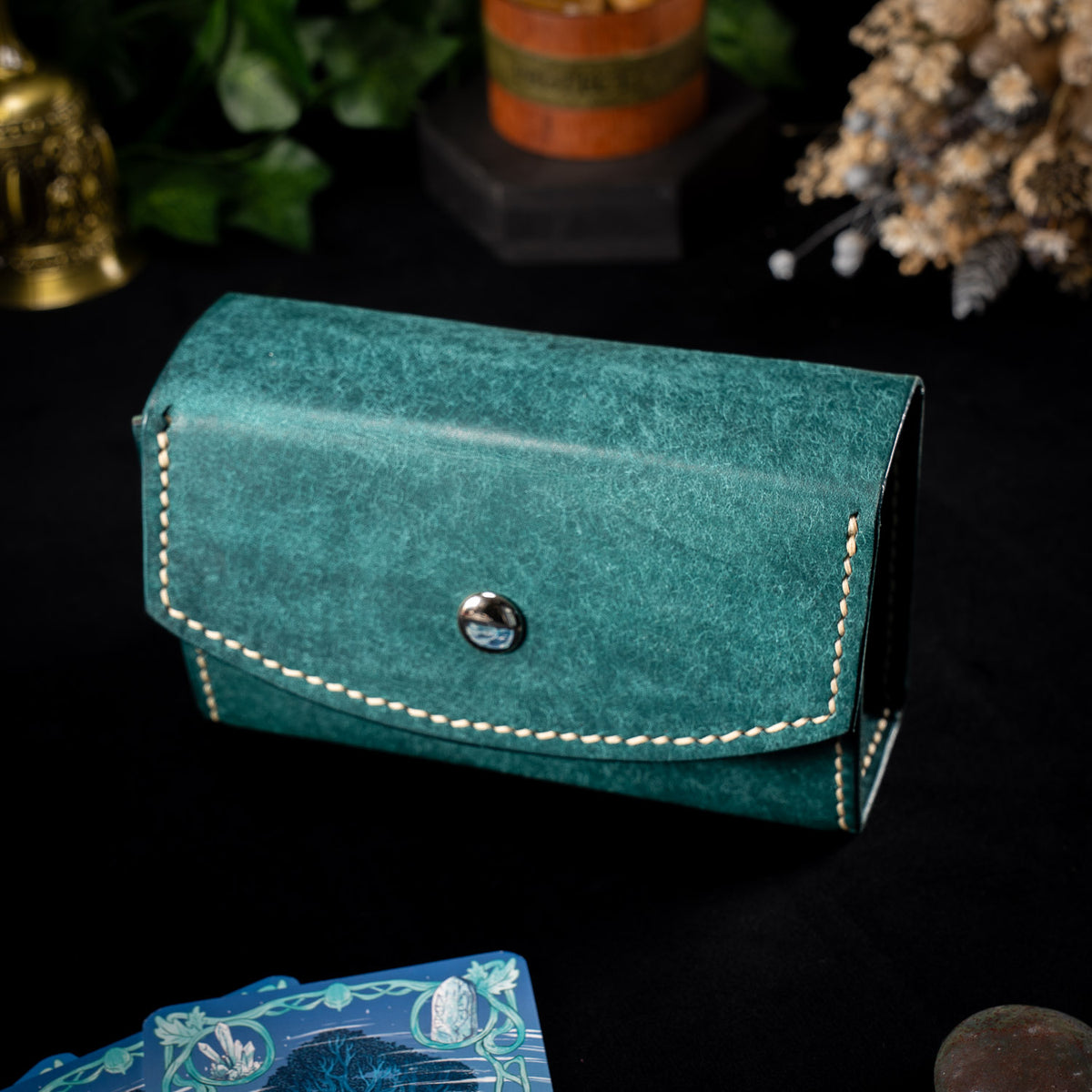 The Oracle deck case in teal Ortensia leather, the Water colourway, closed with cream saddle stitching and a polished silver stud